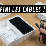 Homme déçu regardant une boîte de smartphone vendue sans câble USB ni chargeur.