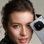 Femme tenant le Huawei Mate X7 gris en main, montrant le grand module photo circulaire.